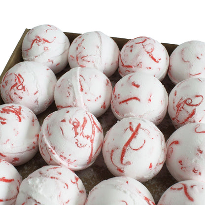 White bath bombs with red swirls in a cardboard box