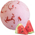 Pink bath bomb with red marbling and two watermelon slices on a white background