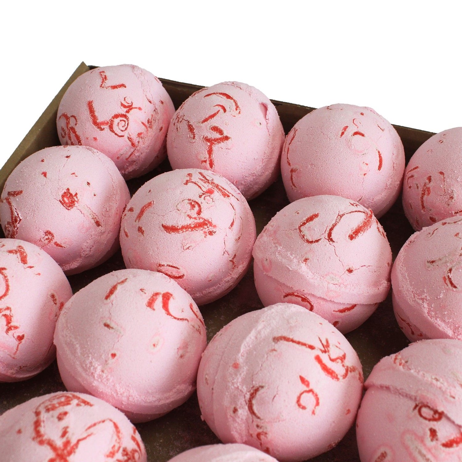Pink bath bombs with red specks in a cardboard box