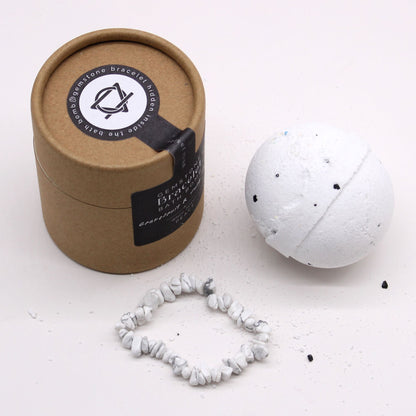 A white beaded bracelet on a white surface, alongside a brown box and a white bath bomb.
